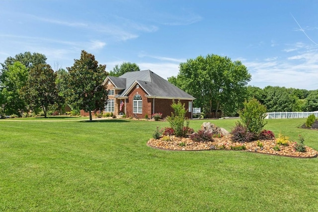 view of front of home featuring brick siding, a front yard, and fence