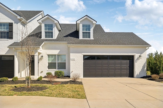 view of front of house with a garage, concrete driveway, and a shingled roof