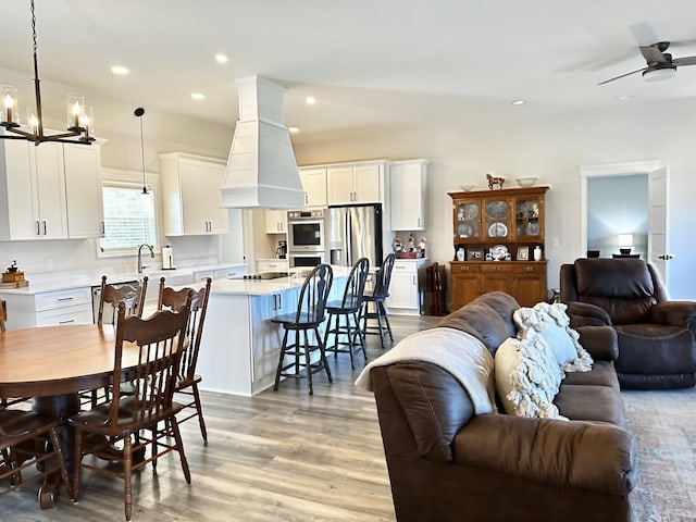 dining room featuring ceiling fan with notable chandelier, light wood finished floors, and recessed lighting