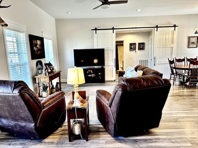 living room with a barn door, ceiling fan, wood finished floors, and recessed lighting