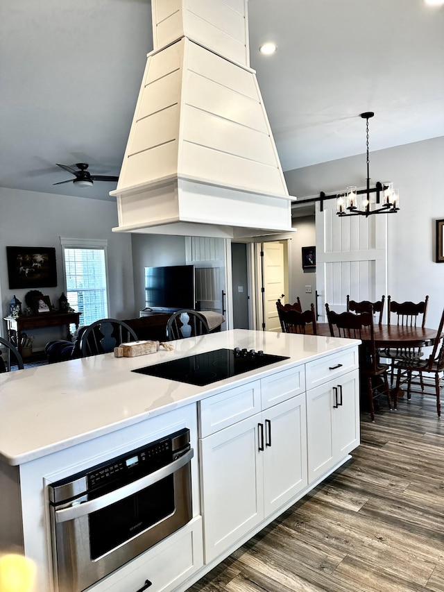 kitchen featuring a barn door, lofted ceiling, open floor plan, custom exhaust hood, and ceiling fan with notable chandelier