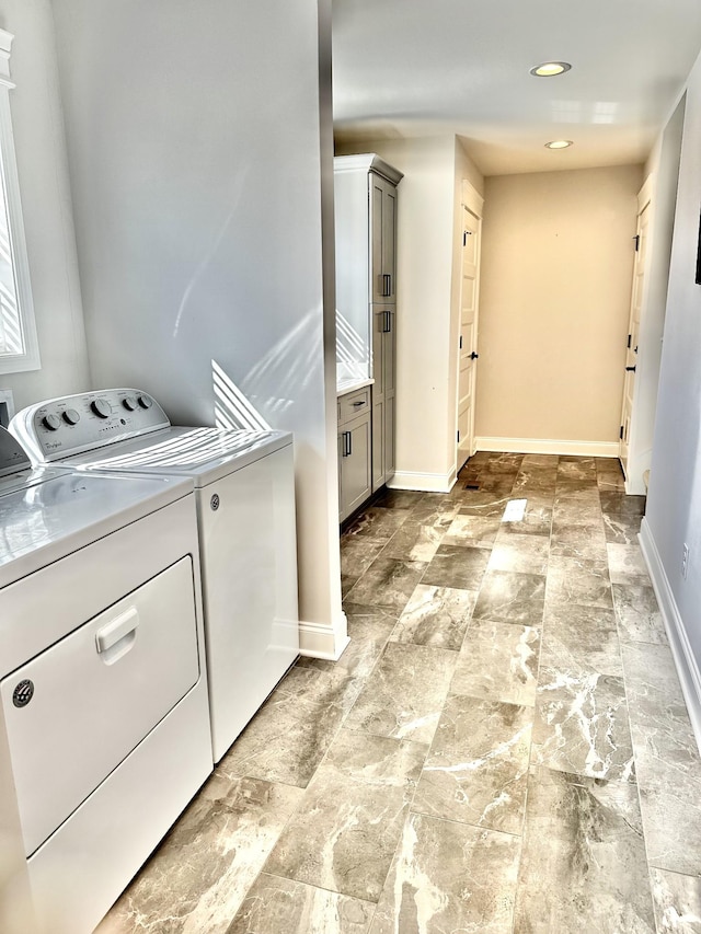 laundry area featuring stone finish floor, laundry area, baseboards, and independent washer and dryer