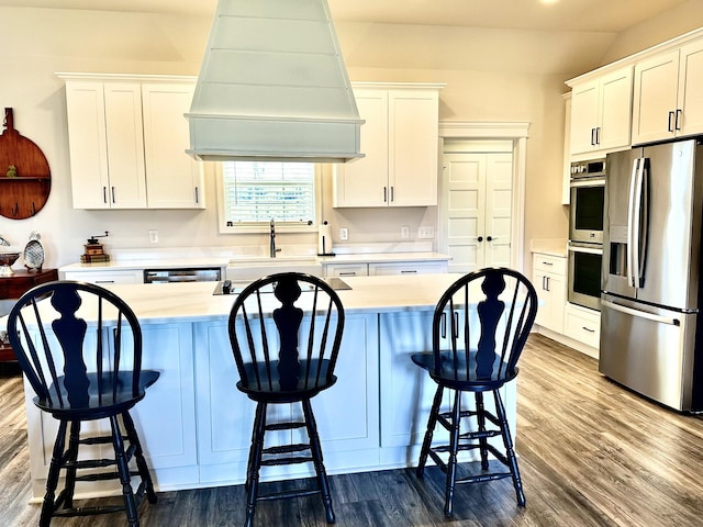 kitchen featuring dark wood-type flooring, a sink, white cabinets, appliances with stainless steel finishes, and custom range hood