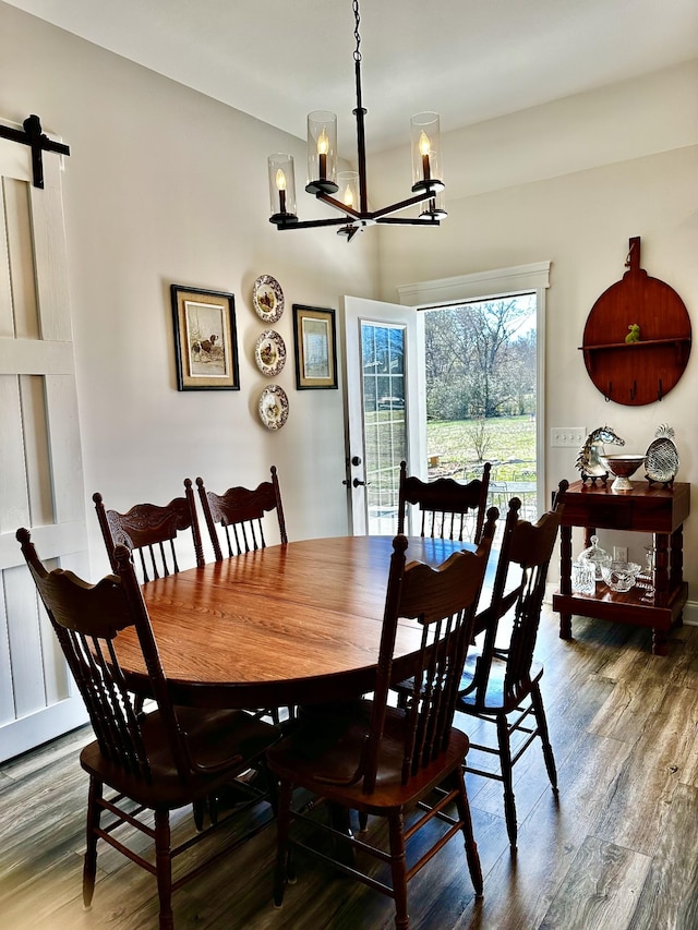 dining area with a chandelier, a barn door, and wood finished floors