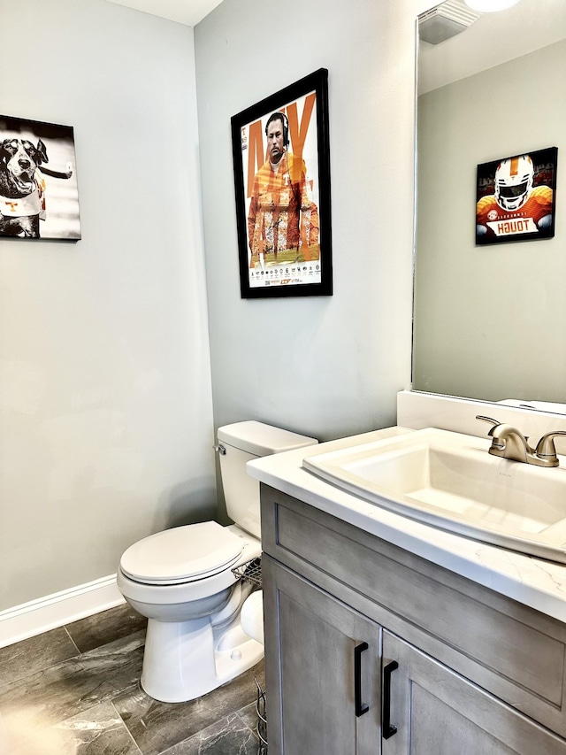 bathroom with toilet, vanity, and baseboards