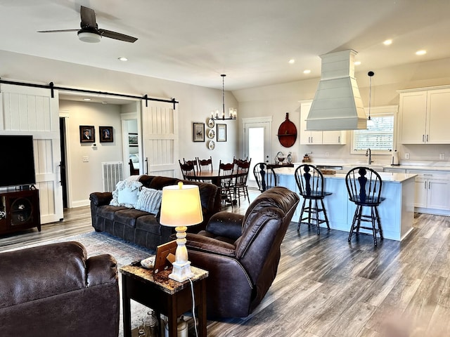 living area with dark wood-style floors, a barn door, a ceiling fan, and recessed lighting