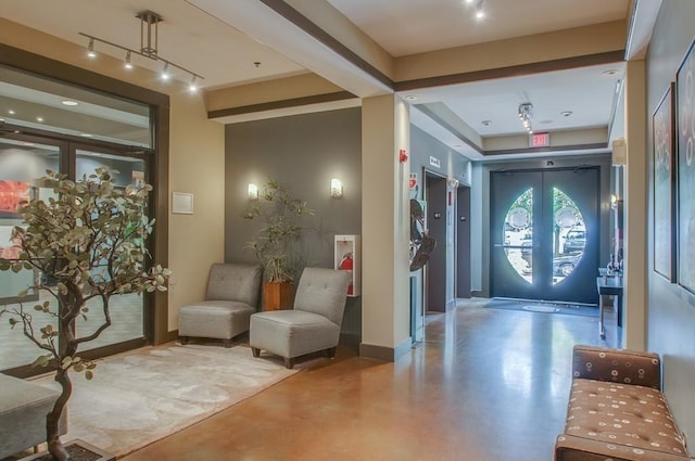 entryway featuring concrete flooring, french doors, rail lighting, and baseboards