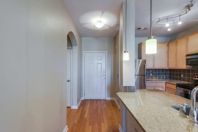 kitchen with stainless steel appliances, visible vents, light wood-type flooring, light brown cabinetry, and tasteful backsplash