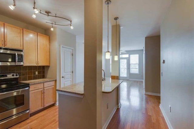 kitchen featuring light stone counters, light brown cabinets, light wood-style floors, appliances with stainless steel finishes, and backsplash