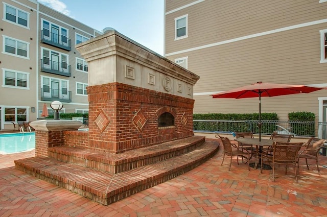 view of patio / terrace featuring an outdoor brick fireplace and fence