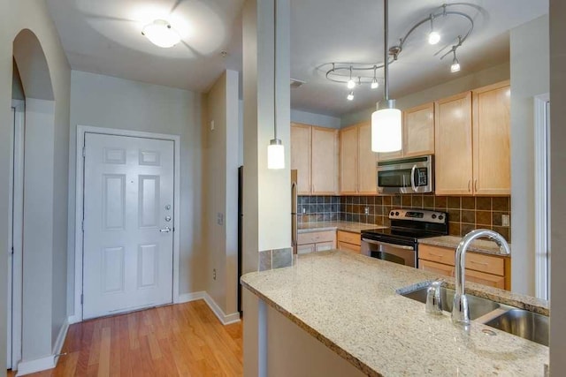 kitchen featuring a sink, appliances with stainless steel finishes, light brown cabinets, and decorative backsplash