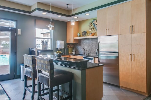 kitchen featuring a breakfast bar, open shelves, stainless steel appliances, decorative backsplash, and light brown cabinets