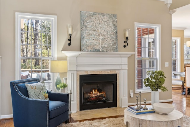 living area with plenty of natural light, a fireplace with flush hearth, baseboards, and wood finished floors