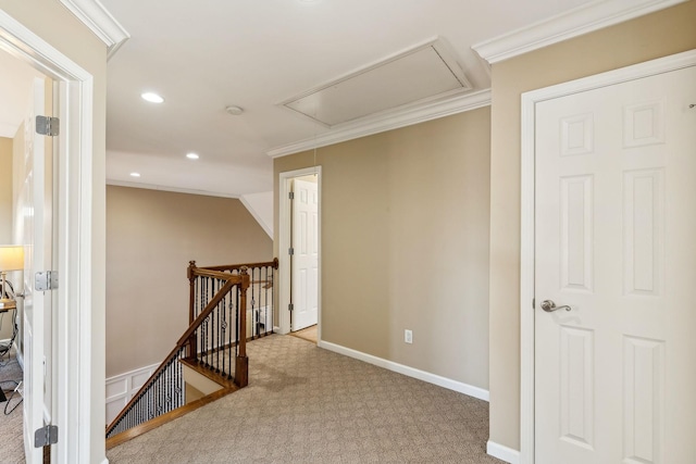 hallway with carpet flooring, an upstairs landing, attic access, and crown molding