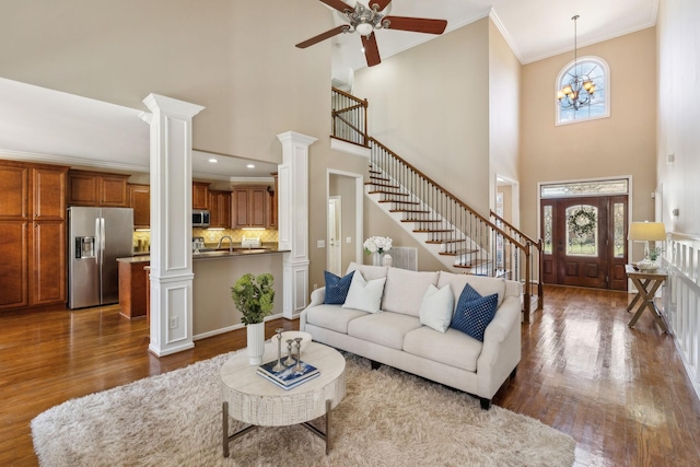 living room featuring stairs, ornate columns, dark wood-type flooring, and crown molding