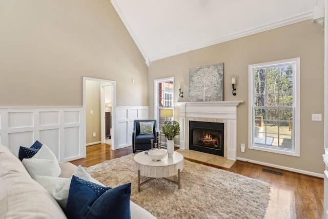 living area featuring vaulted ceiling, ornamental molding, wood finished floors, and visible vents