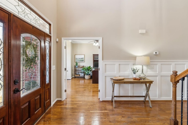 foyer entrance with plenty of natural light, a decorative wall, and wood finished floors