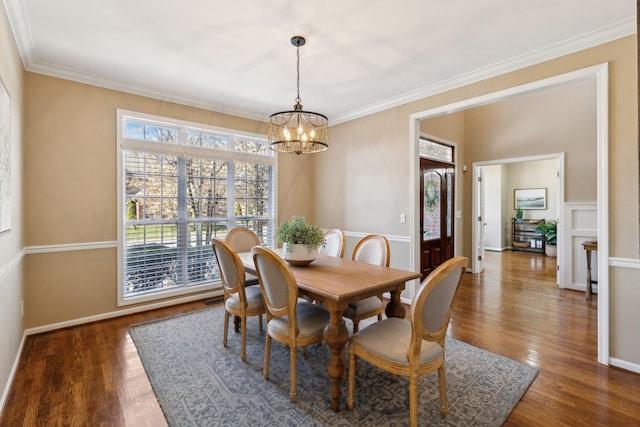 dining room featuring baseboards, ornamental molding, wood finished floors, and a notable chandelier