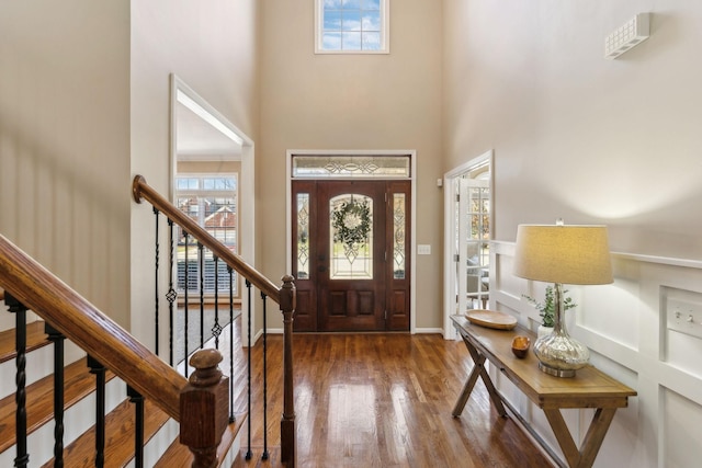 entryway with a towering ceiling, wood finished floors, a wealth of natural light, and baseboards