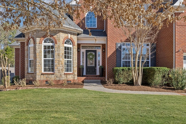 doorway to property featuring crawl space, brick siding, and a lawn