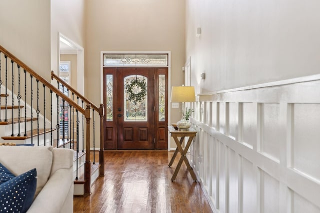 foyer with stairs, a towering ceiling, and wood finished floors