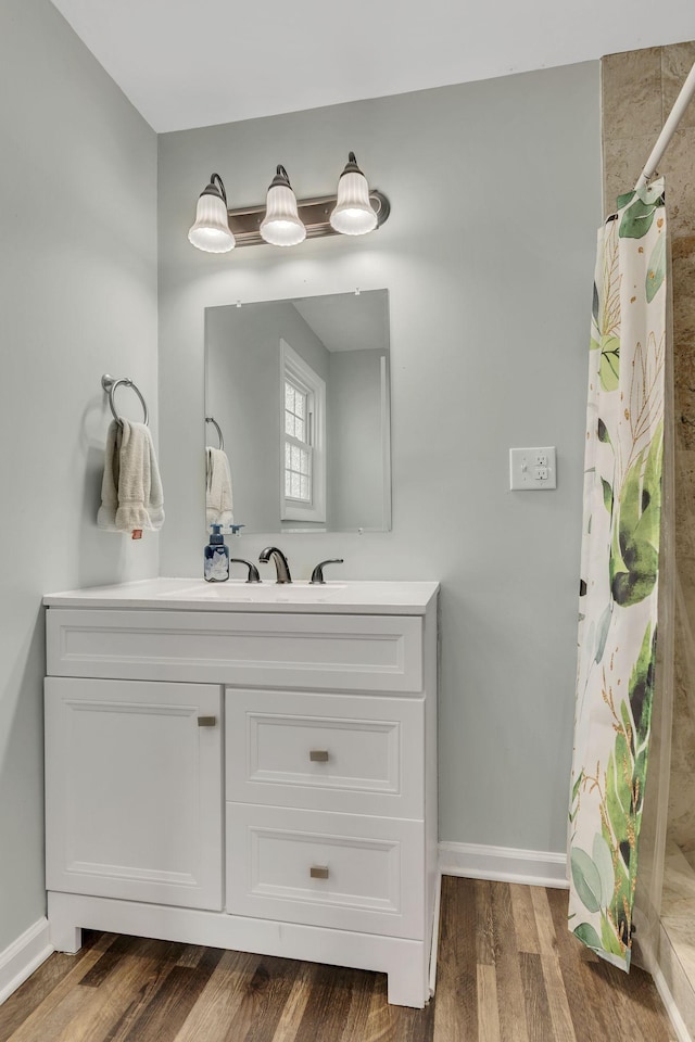 bathroom with curtained shower, vanity, baseboards, and wood finished floors