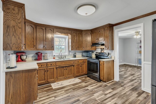 kitchen featuring a sink, under cabinet range hood, light countertops, and electric stove