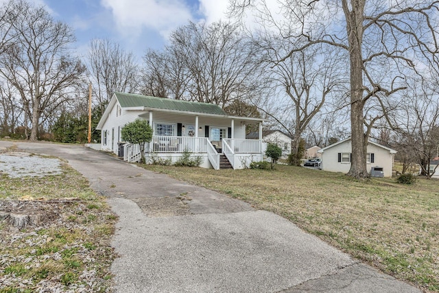 view of front of house with covered porch, metal roof, a front lawn, and aphalt driveway