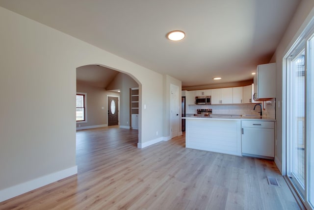 kitchen featuring light wood-style floors, open floor plan, light countertops, appliances with stainless steel finishes, and tasteful backsplash