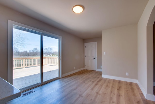 empty room with light wood-style flooring, visible vents, and baseboards