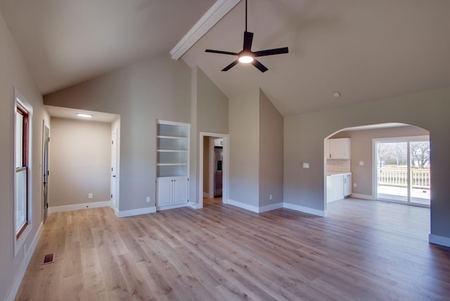 unfurnished living room featuring baseboards, visible vents, arched walkways, light wood-type flooring, and beam ceiling