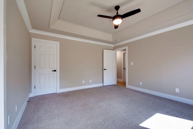 unfurnished room featuring ornamental molding, a raised ceiling, carpet flooring, and baseboards