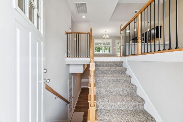 stairway with recessed lighting, visible vents, an inviting chandelier, and wood finished floors