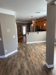 interior space with ornamental molding, dark wood-style flooring, and baseboards