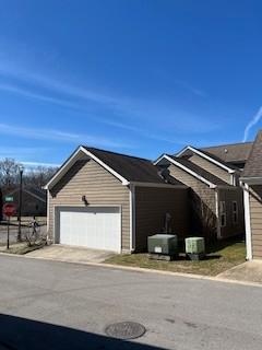 view of front of property featuring driveway, an attached garage, and central air condition unit