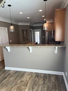 kitchen featuring ornamental molding, wood finished floors, light stone countertops, and baseboards