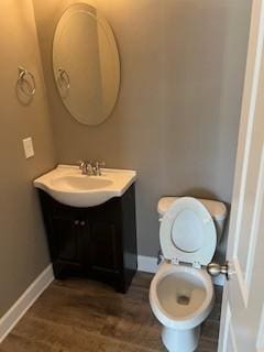 bathroom with toilet, baseboards, wood finished floors, and vanity