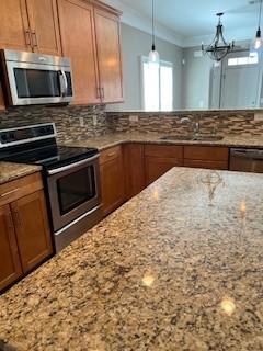 kitchen with appliances with stainless steel finishes, backsplash, and light stone counters