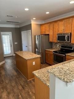 kitchen with crown molding, appliances with stainless steel finishes, brown cabinets, and a center island