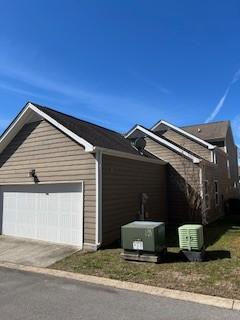 view of side of home with a garage, driveway, and central AC unit