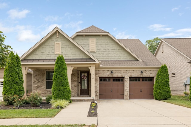 craftsman-style home with brick siding, a shingled roof, a porch, an attached garage, and driveway