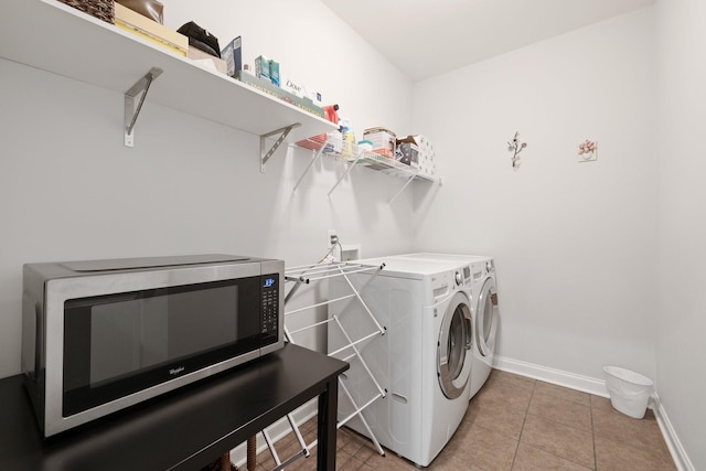 laundry area with laundry area, washer and clothes dryer, baseboards, and light tile patterned floors