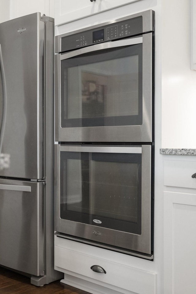 room details featuring stainless steel appliances, white cabinets, and dark wood-type flooring