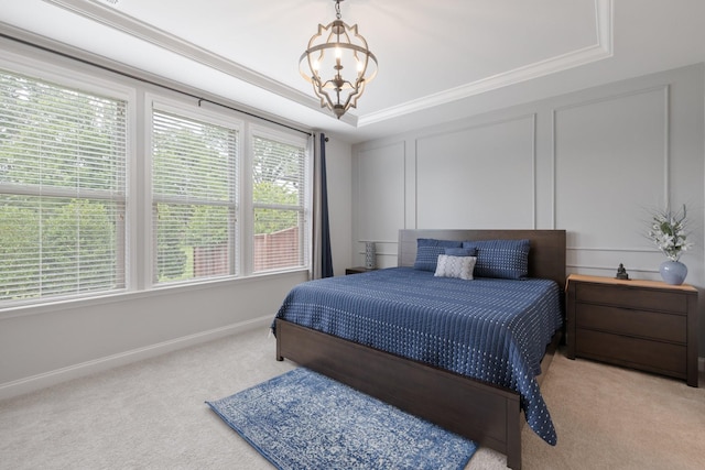 carpeted bedroom with crown molding, a tray ceiling, an inviting chandelier, and a decorative wall