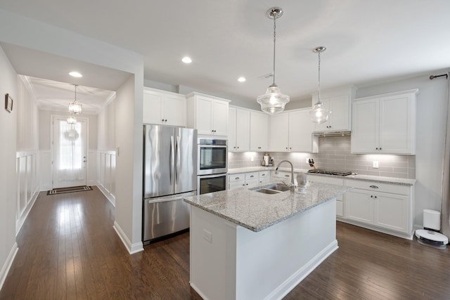 kitchen with dark wood finished floors, a sink, stainless steel appliances, white cabinetry, and backsplash