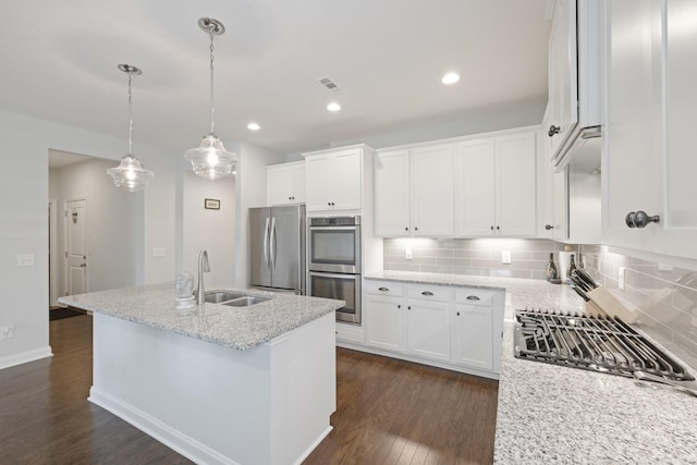 kitchen with stainless steel appliances, dark wood-style flooring, a sink, white cabinetry, and backsplash