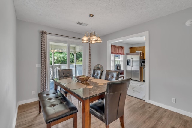 dining area featuring a chandelier, visible vents, light wood-style floors, and baseboards