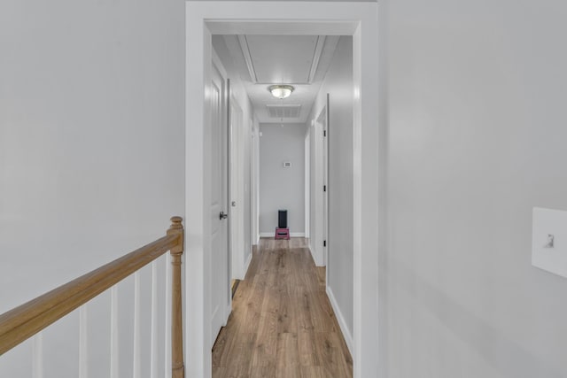 corridor with visible vents, attic access, light wood-style floors, an upstairs landing, and baseboards