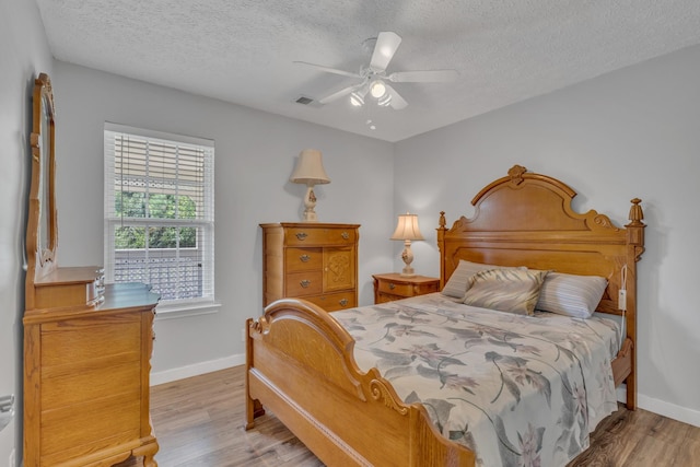 bedroom with baseboards, visible vents, and wood finished floors