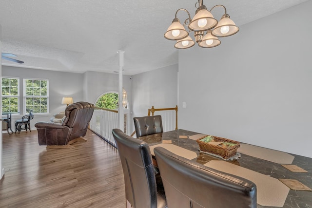 dining room featuring an inviting chandelier, a textured ceiling, and wood finished floors